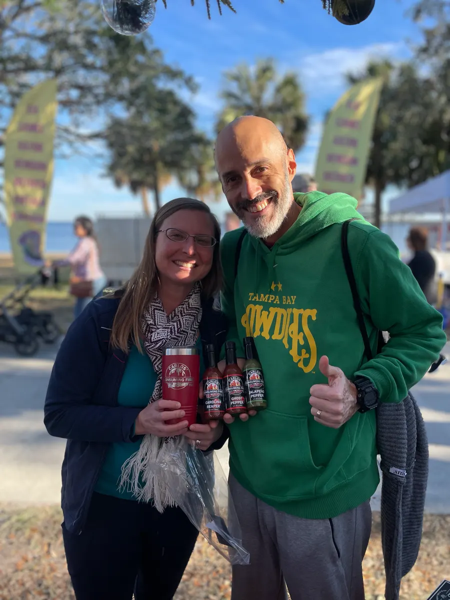 Couple with a branded tumbler and a three-bottle gift pack at a waterfront market